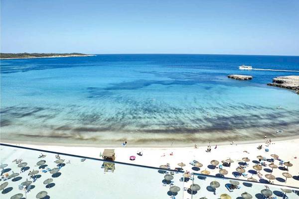 Aussicht von Perla Hotel auf einen weißen Sandstrand mit vielen Gästen und Sonnenschirmen