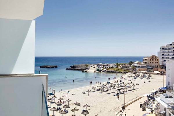 Aussicht vom Balkon des Perla Hotels auf den Strand mit vielen Liegestühlen und Sonnenschirmen.