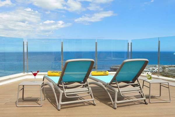 Zwei Loungestühle auf der Dachterrasse des Perla Hotels mit Blick auf das Meer.
