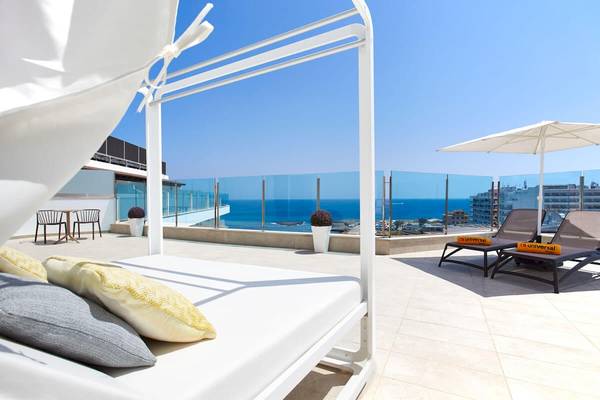 Hotelterrasse mit Meerblick im Perla Hotel, mit Sonnenbetten, Sonnenschirm und Pflanzen.