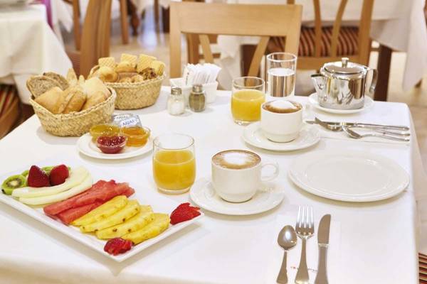 Frühstücksbuffet im Perla Hotel mit Obst, Brot, Kaffee und Tee.