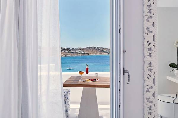 Terrasse mit Meerblick im Katikies Villas Mykonos Hotel, mit einem Tisch, Getränken und einer schönen Aussicht auf das Meer.
