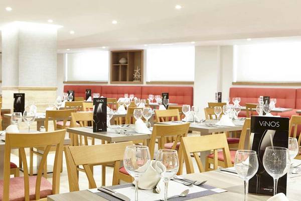 Innenbereich des Perla Hotels mit einem gut eingerichteten Restaurant, das mehrere Tische und Stühle zeigt.