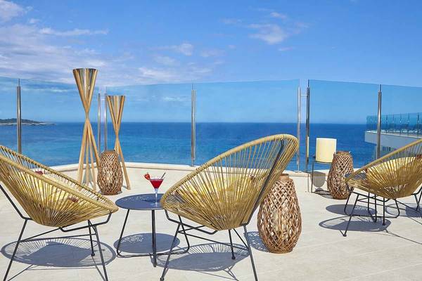 Terrasse des Perla Hotels mit Blick auf das Meer und modernen Möbeln.