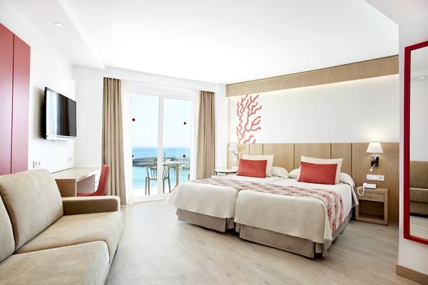 Doppelzimmer im Perla Hotel mit Meerblick, zwei Betten, Schreibtisch, Fernseher und offener Terrasse.