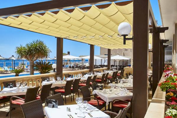 Außenterrasse des Romantica Hotels mit Sitzplätzen, Tischen und Sonnenschirmen am Meer