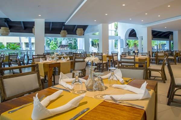 Innenansicht des Restaurants im Coral Costa Caribe Beach Resort mit gedeckten Tischen und Stühlen.