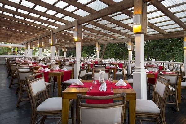 Restaurant im Coral Costa Caribe Beach Resort mit gedeckten Tischen und Stühlen.