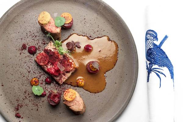 Ein Teller mit gebratenem Fleisch, Beilagen und roter Sauce, serviert auf einem grauen Teller.