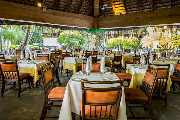 Innenansicht des Restaurants im Coral Costa Caribe Beach Resort mit gedeckten Tischen und Stühlen.