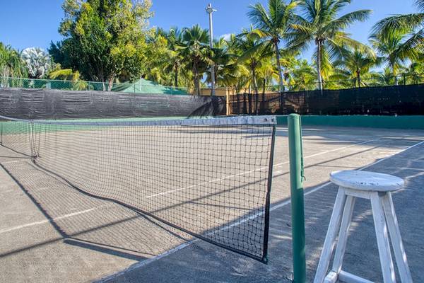 Tennisplatz im Coral Costa Caribe Strandresort mit Netz, Schatten und Palmen im Hintergrund