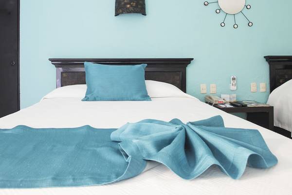 Bett im Hotelzimmer des Coral Costa Caribe Beach Resort mit blauer Bettwäsche und Kissen.