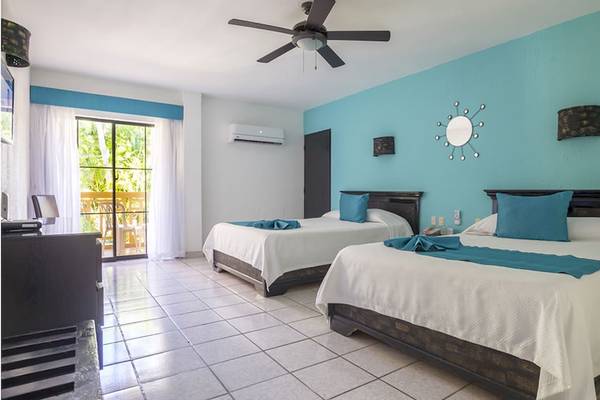 Schlafzimmer im Coral Costa Caribe Beach Resort mit zwei Betten, blauen Wänden und einer Klimaanlage.