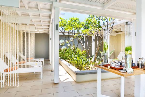 Loungebereich im Radisson Blu Azuri Resort & Spa mit weißen Liegen und einer grünen Pflanzenecke.