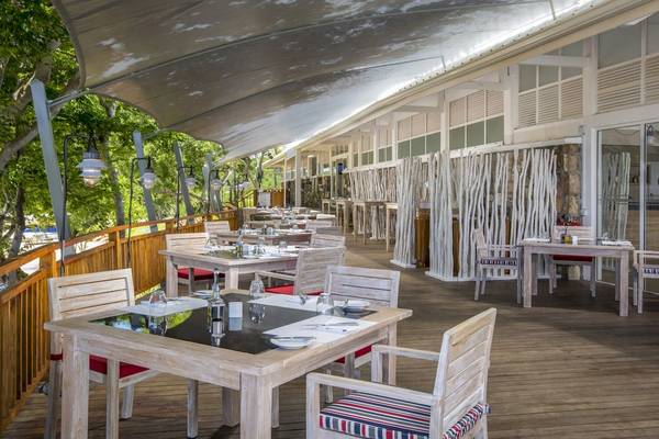 Terrasse des Radisson Blu Azuri Resort & Spa mit gedeckten Tischen und Stühlen.