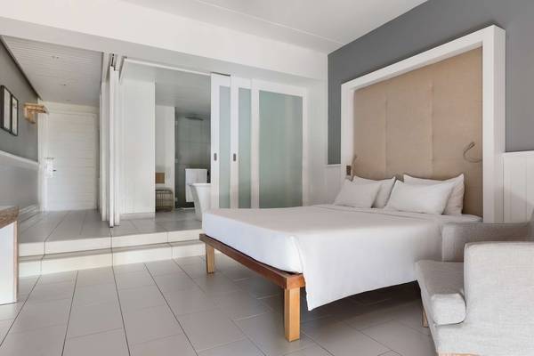 Schlafzimmer im Radisson Blu Azuri Resort & Spa mit weißem Bett und modernen Möbeln.
