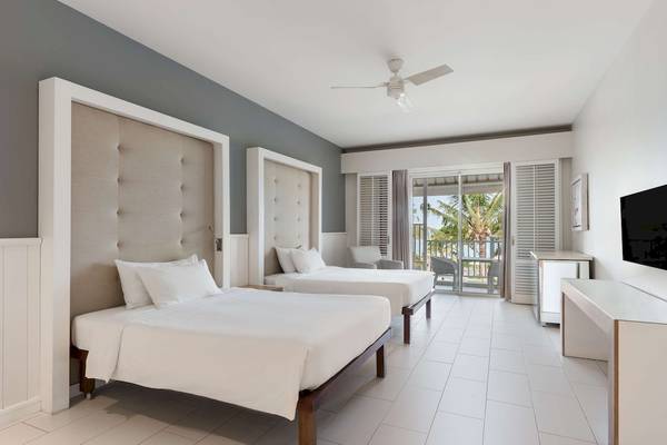 Innenansicht eines Schlafzimmers im Radisson Blu Azuri Resort & Spa mit zwei Betten und einem Balkon.