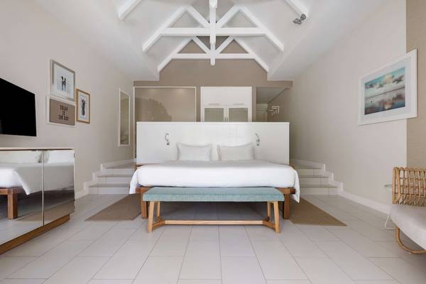 Schlafzimmer im Radisson Blu Azuri Resort & Spa mit weißen Möbeln, einem Bett und einer Treppe.
