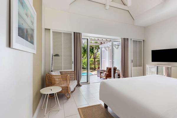 Innenansicht eines Zimmers im Radisson Blu Azuri Resort & Spa mit weißem Bett und Balkon.