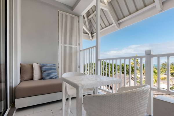 Ein Balkon des Radisson Blu Azuri Resort & Spa mit Blick auf das Meer und eine Sitzecke mit Kissen.