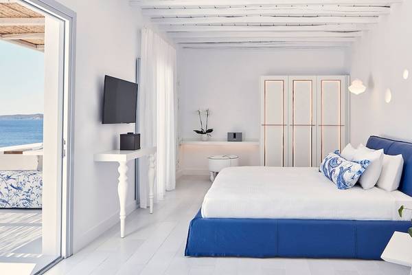 Schlafzimmer im Katikies Villas Mykonos mit Blick auf das Meer, weiße Wände, blaues Bett und Nachttisch