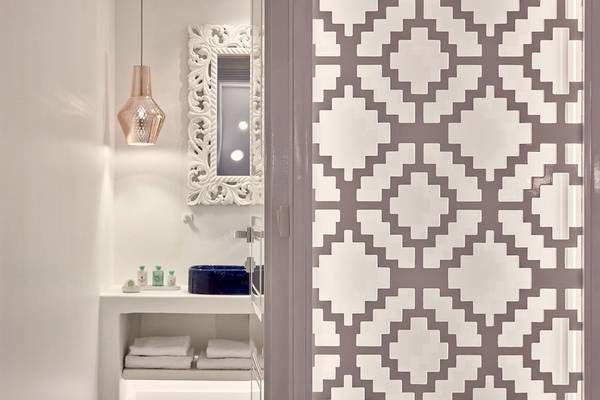 Innenansicht des Badezimmers in den Katikies Villas Mykonos mit weißen Wänden, grauen Mustern und einer blauen Badewanne.