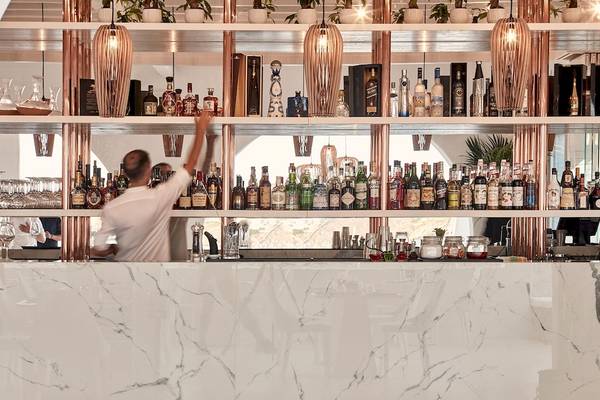 Ein Barkeeper steht im Cocktailbereich der Katikies Villas Mykonos und serviert Getränke.