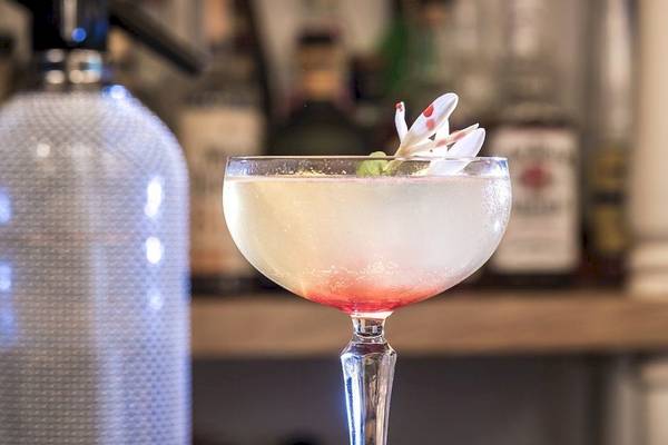 Ein Cocktail in einem Glas auf einer Bar mit einer Blume obenauf.