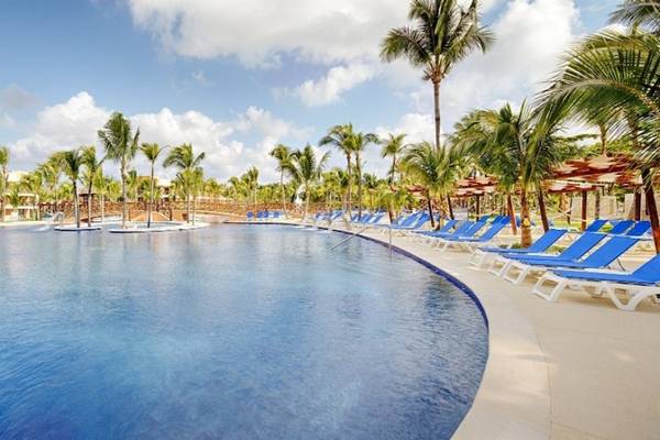 Außenpool im Barcelo Maya Beach Hotel mit blauen Liegestühlen und Palmen