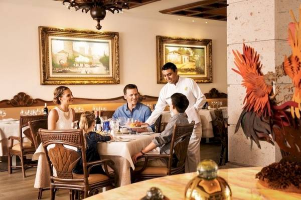 Familie in einem eleganten Restaurant des Barcelo Maya Beach Hotels, das Essen serviert wird