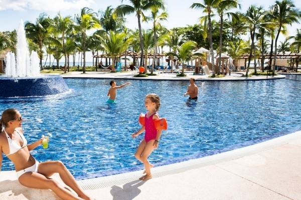 Familie am Pool des Barcelo Maya Beach Hotel, mit einer Frau und zwei Kindern.