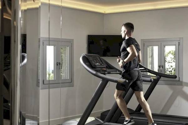 Mann im Fitnessraum der Katikies Villas Mykonos läuft auf einem Laufband.