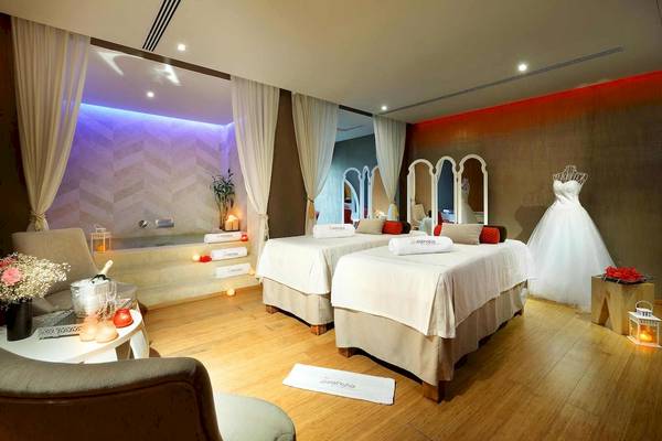 Behandlungsraum im Grand Palladium Spa mit zwei Betten, Whirlpool und Hochzeitskleid.
