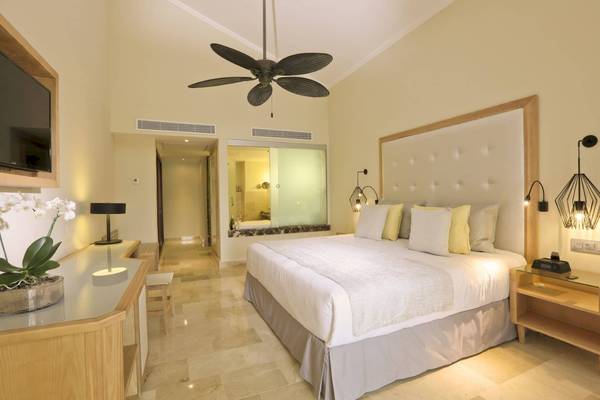 Luxuriöses Schlafzimmer im Grand Palladium Palace Resort & Spa mit einem großen Bett, Nachttischen und einer modernen Einrichtung.