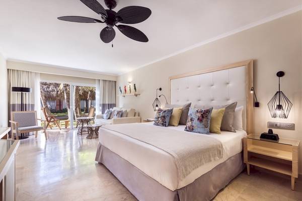 Schlafzimmer im Grand Palladium Palace Resort & Spa mit Bett, Kissen und Nachttischen.