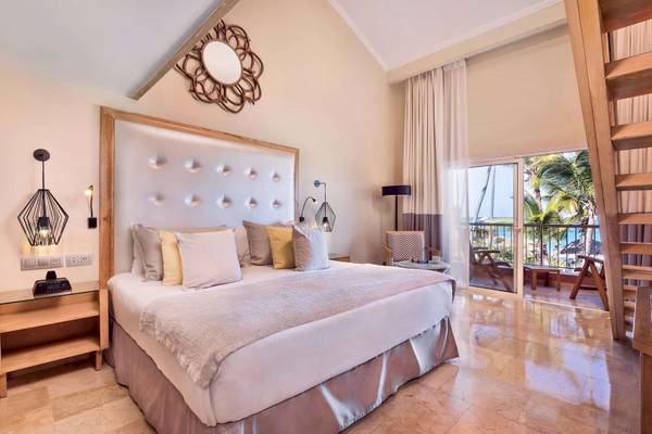 Schlafzimmer im Grand Palladium Palace Resort & Spa mit großem Bett, Marmorboden und Blick auf den Ozean.