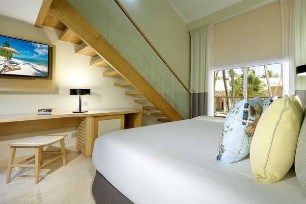 Schlafzimmer im Grand Palladium Palace Resort & Spa mit Fernseher, Schreibtisch und Bett.