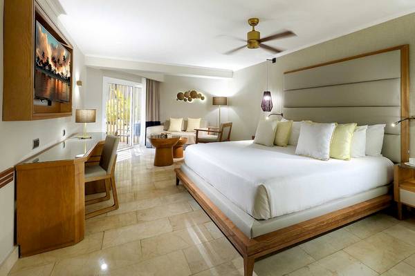 Suite-Schlafzimmer im Grand Palladium Palace Resort & Spa mit großem Bett, Holzmöbeln und moderner Einrichtung.