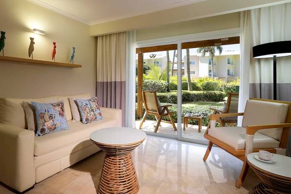 Wohnzimmer des Grand Palladium Palace Resort & Spa mit Sofa, Tisch und Terrassenzugang