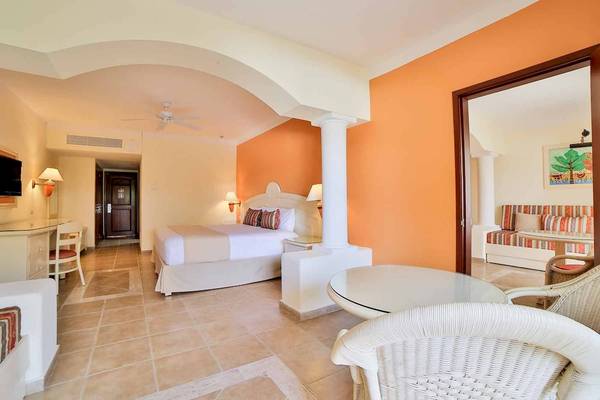 Das geräumige Zimmer im Bahia Principe Grand Coba Hotel mit Bett, Tisch und Stühlen.