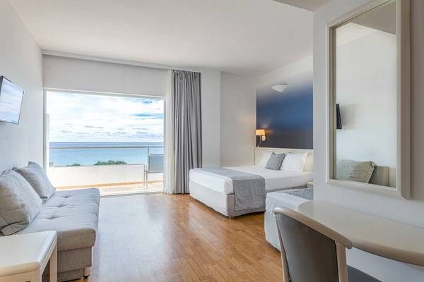 Zimmer im Blue Sea Beach Resort mit Meerblick, inklusive Bett, Sofa, Schreibtisch und Fernseher.