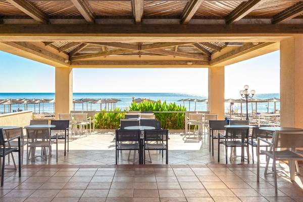 Terrasse des Blue Sea Beach Resorts mit Blick auf das Meer und Strandschirme.