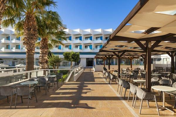 Außenbereich des Blue Sea Beach Resort Hotels mit Tischen, Stühlen und Palmen.