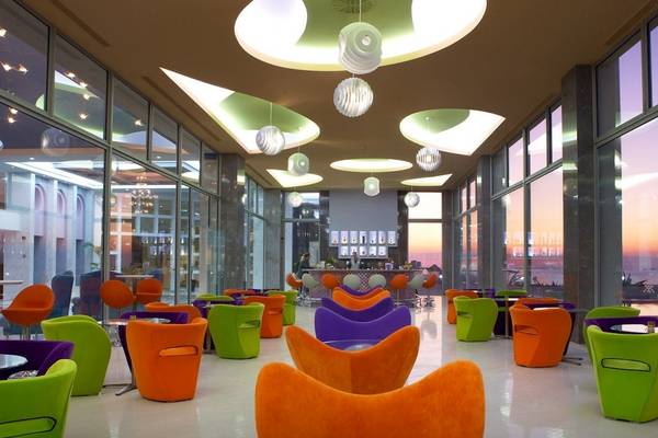 Hotellobby des Atrium Platinum Luxury Resort Hotel & Spa mit farbenfrohen Sesseln und einer Bar im Hintergrund.