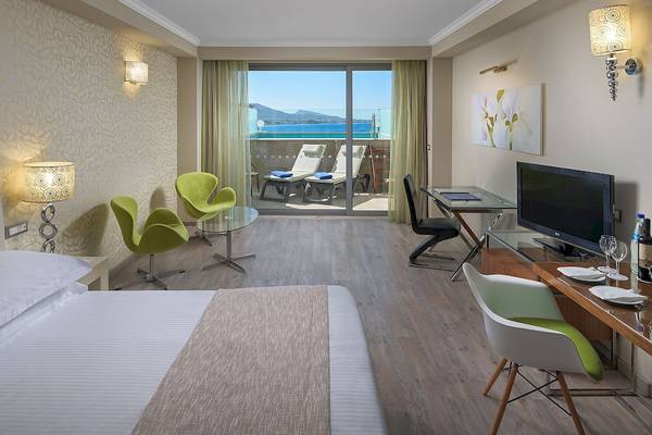 Innenansicht eines Hotelzimmers im Atrium Platinum Luxury Resort Hotel & Spa mit Balkon, Fernseher und Schreibtisch.