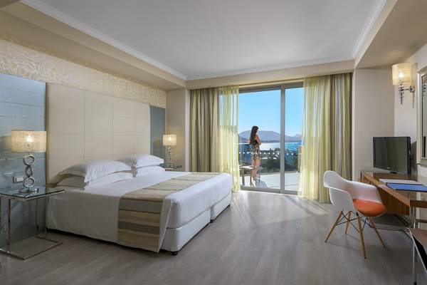 Eine Hotelsuite mit Blick auf das Meer und eine Frau auf dem Balkon.