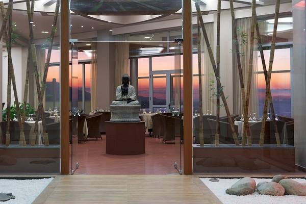 Innenansicht des Atrium Platinum Luxury Resort Hotel & Spa Restaurant mit Buddha-Statue und Glaswänden.