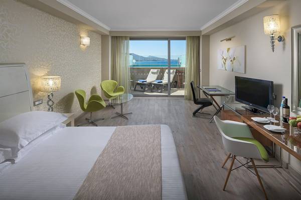 Innenansicht eines Hotelzimmers mit Blick auf einen Pool und einen Berg