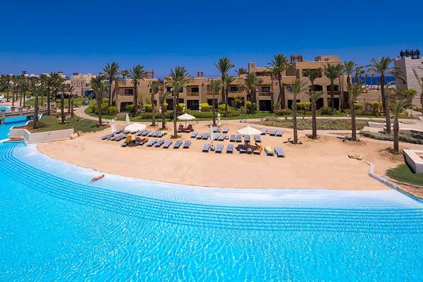 Außenbereich des PickAlbatros Oasis Port Ghalib Hotels mit Pool, Liegestühlen und Gebäuden.