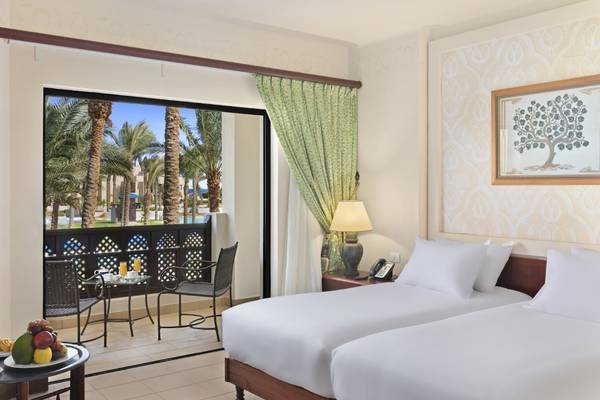 Doppelzimmer im PickAlbatros Oasis Port Ghalib Hotel mit Balkon und Ausblick auf Palmen.